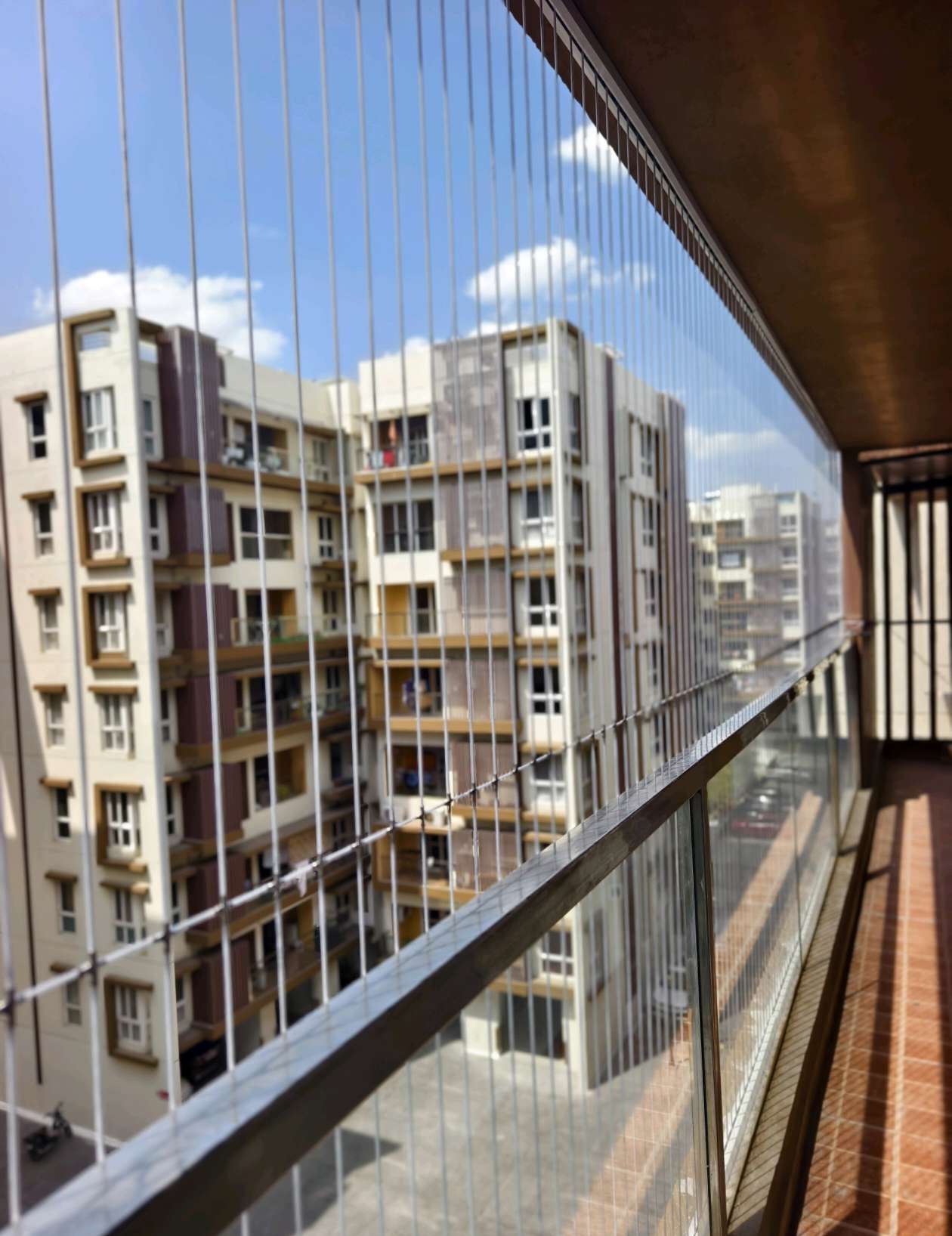 Balcony with vertical grill cables facing neighboring apartments — real YPL work shown for Athipet customers