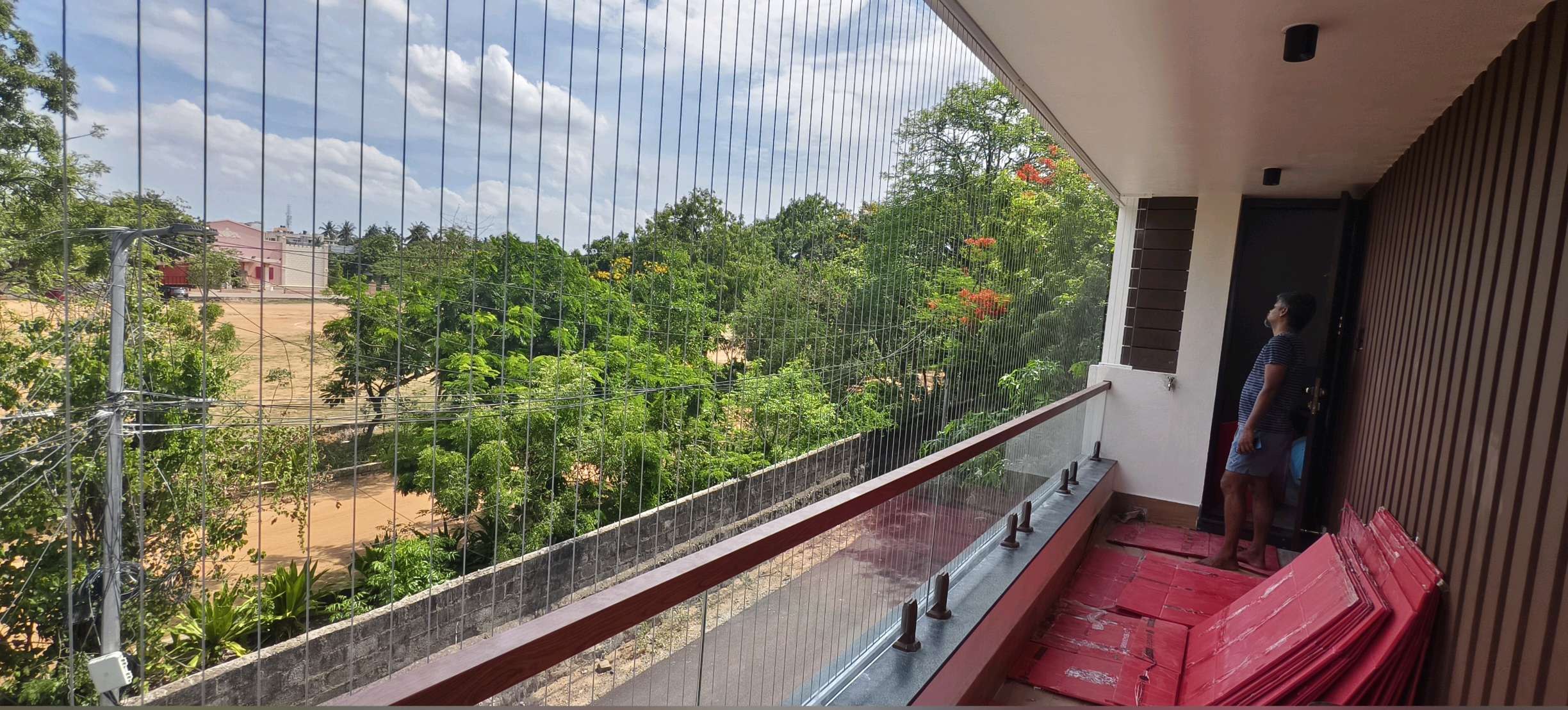 Wide balcony protected with grill cables above a glass railing — real YPL work shown for Ullagaram customers