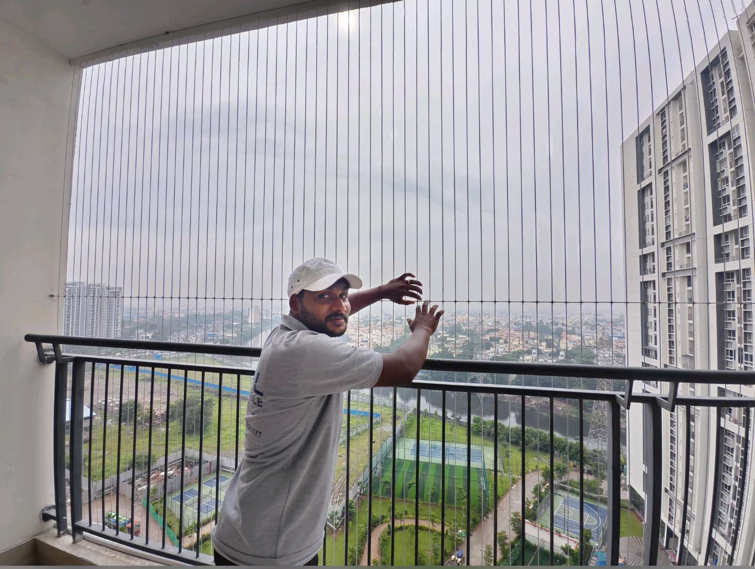 Installer measuring the grill cables above a balcony railing — real YPL work shown for Kovur customers