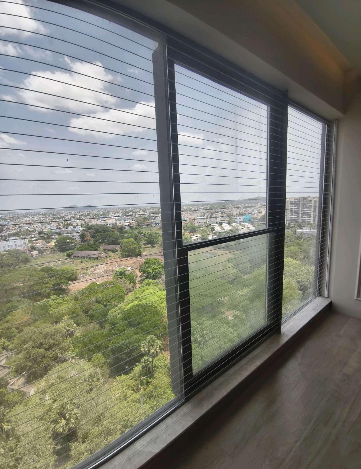 Sliding window overlooking trees behind invisible grill cables — real YPL work shown for Ennore customers