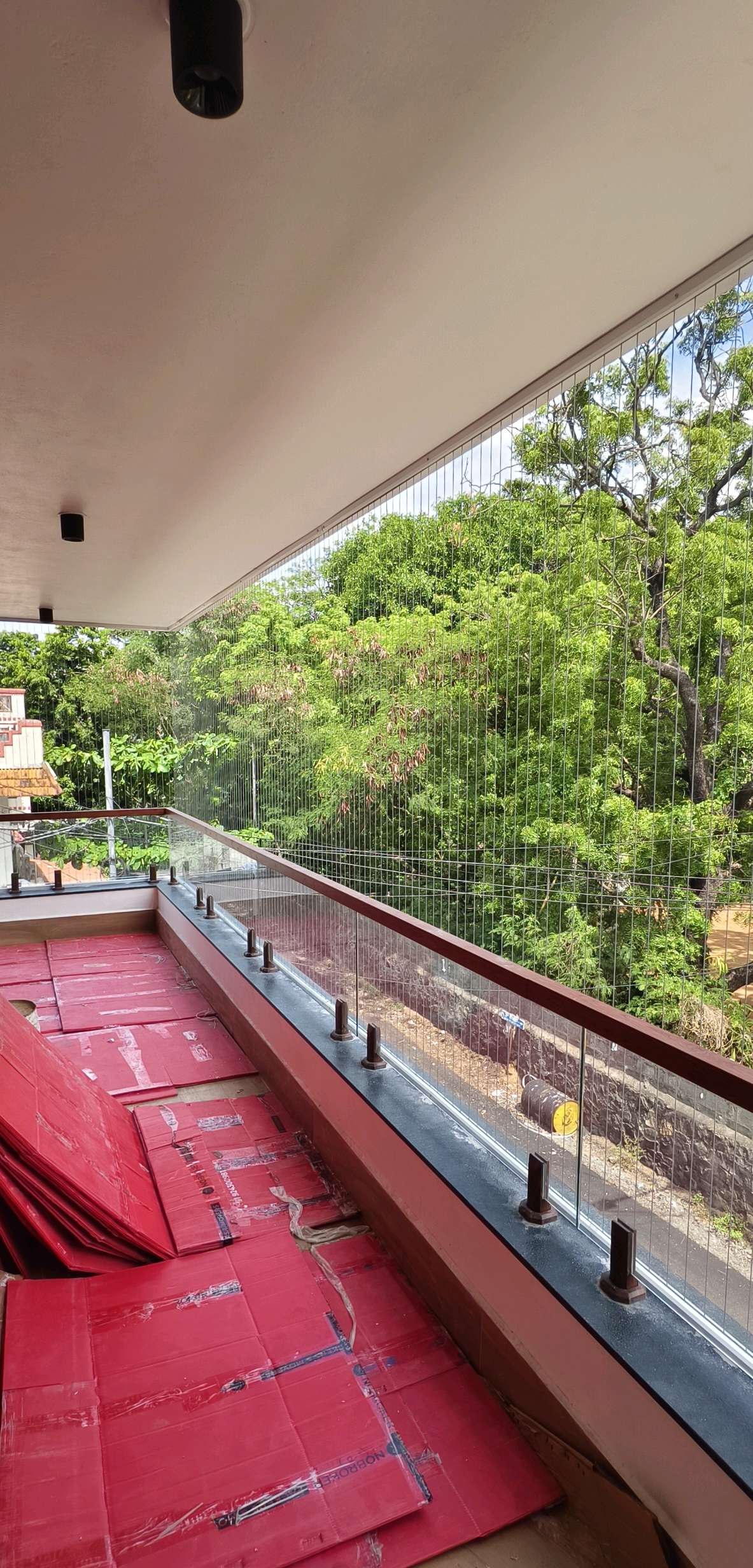 Balcony corner with glass railing and grill cables — real YPL work shown for Sadras customers
