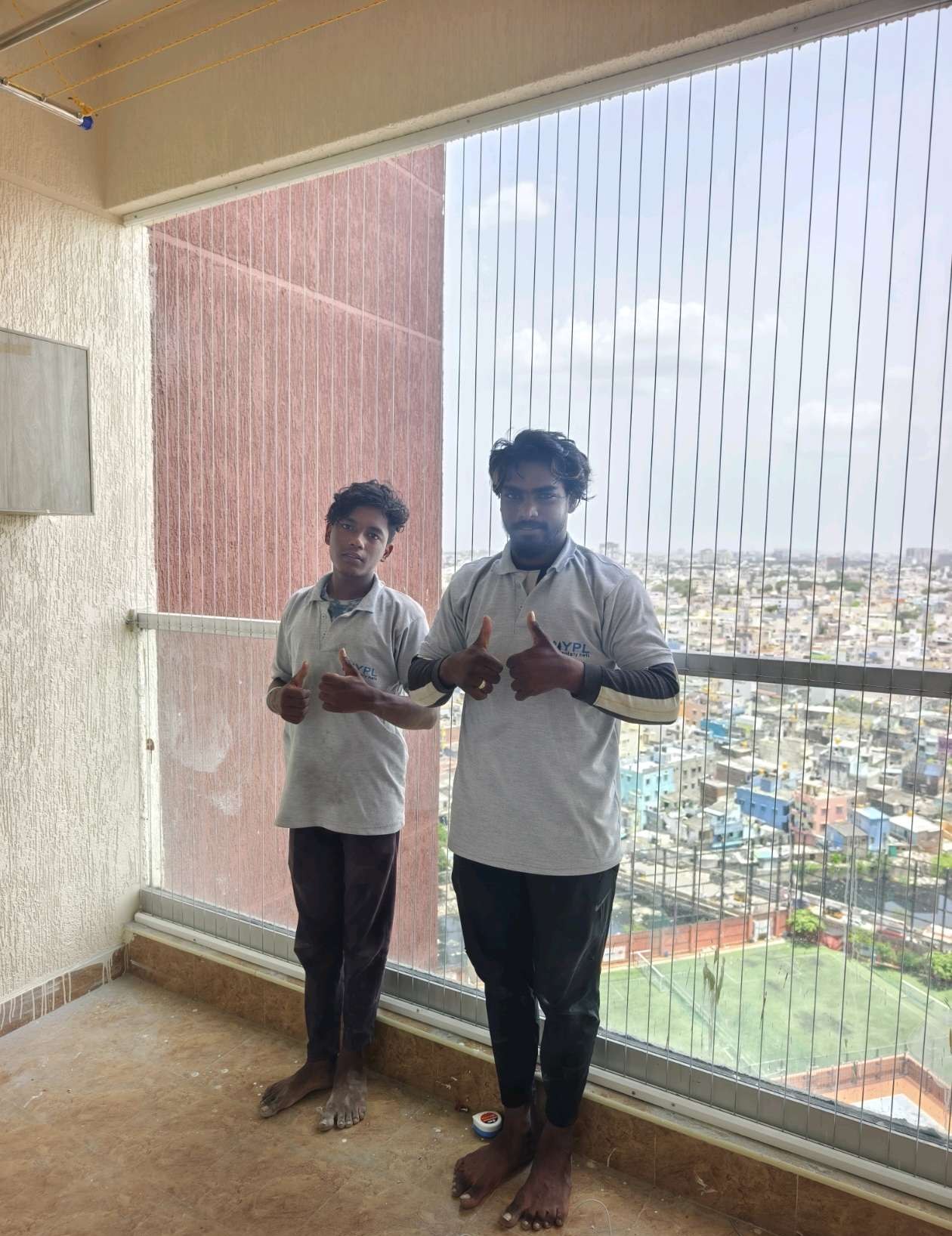 Two workers fitting cables along a balcony opening — real YPL work shown for Chintadripet customers