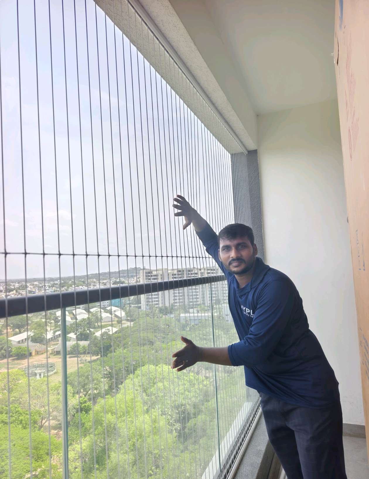 Installer working on invisible grill cables beside a balcony railing