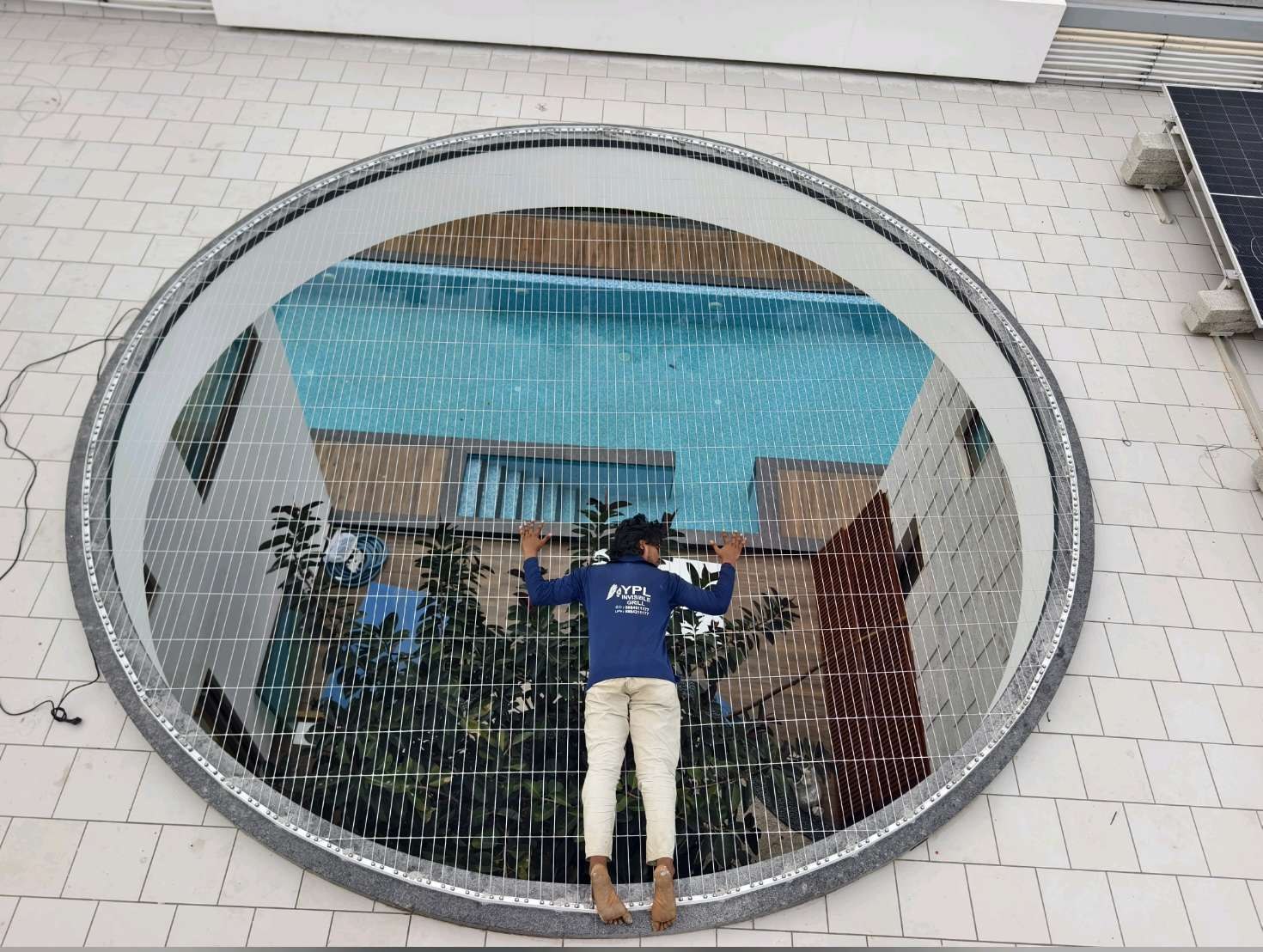 Circular building window with a worker fitting fine grill cables