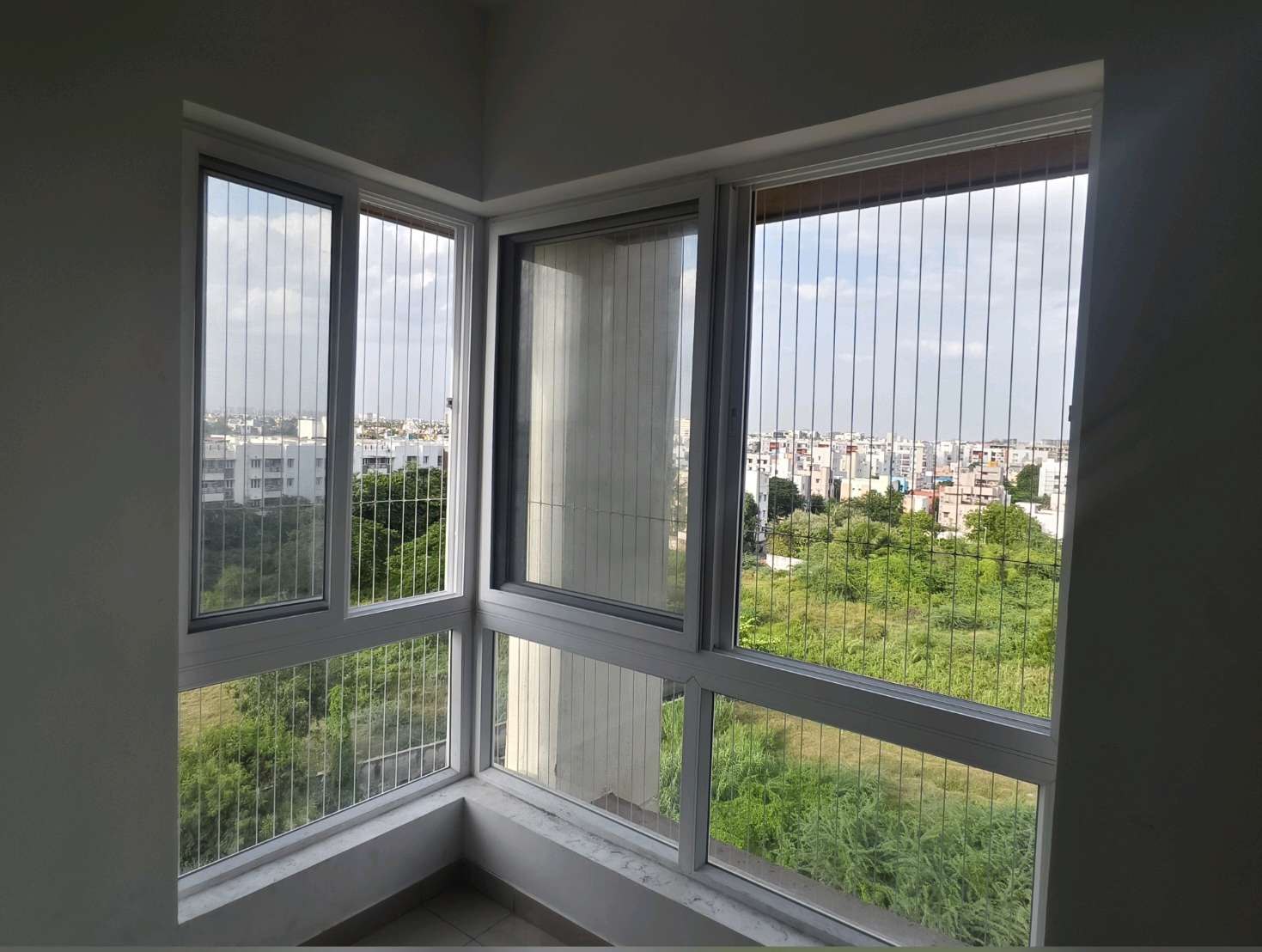 Corner window fitted with vertical invisible grill cables — real YPL work shown for Kottivakkam customers
