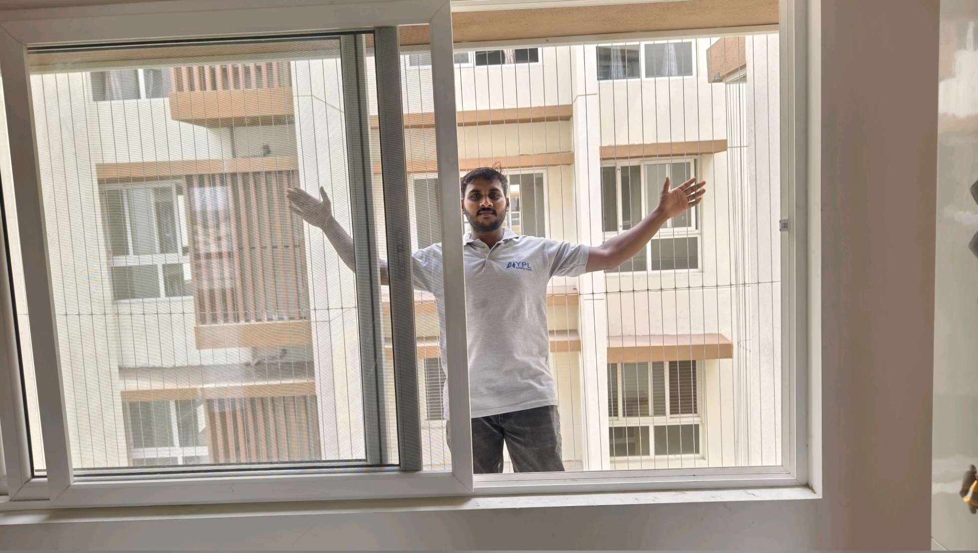 Installer fitting cables to a residential window — real YPL work shown for Kovalam customers