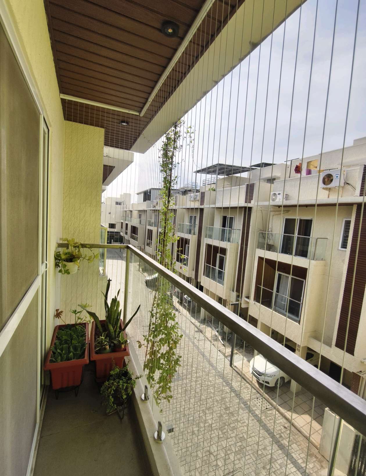 Balcony with fine grill cables overlooking neighboring homes — real YPL work shown for Puzhal customers